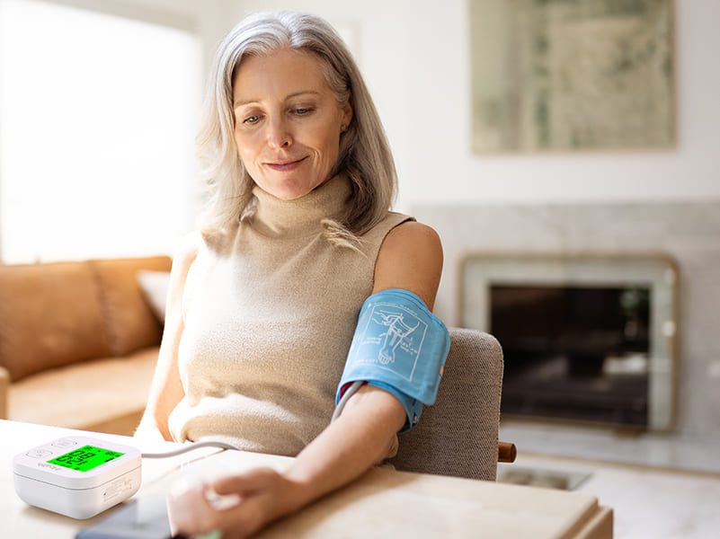 Fotografía de una mujer mayor midiendo su presión arterial con el Tensiómetro iHealth digital y de bluetooth