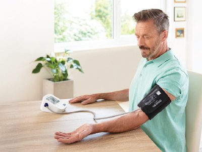 Imagen de un hombre con un tensiómetro Omron silver para medir presión arterial.